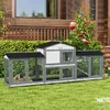 A multi-level wooden hutch for small animals, set up on a green lawn in front of a wooden house. Produktbild-Vorschau