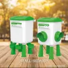Two chicken feeders/drinkers on a wooden surface with a blurred natural background. Produktbild-Vorschau
