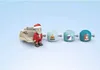 A toy Santa Claus figure with a sleigh and three wheeled accessories, displayed on a light blue background. Podgląd zdjęcia produktu