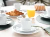 A breakfast table setting with coffee cups, a croissant, orange juice, and a bundt cake. Produktbild-Vorschau