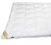A white quilted blanket is shown from a diagonal angle, with a white background. Podgląd zdjęcia produktu