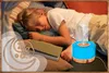 A young boy sleeping in bed next to an aroma diffuser. Produktbild-Vorschau