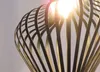 A close-up shot of a modern pendant light fixture with a black, cage-like shade and a bright light bulb inside. Produktbild-Vorschau