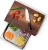 A wooden cutting board with a stainless steel drawer filled with chopped vegetables, and ingredients on top of the board. Anteprima dell’immagine prodotto