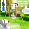 A baby is sitting in a swing set in a backyard. Produktbild-Vorschau