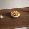 A bowl of fruit on a wooden table. Produktbild-Vorschau