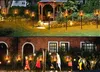 Two images showing solar torch lights in a garden and on a pathway in front of a house. Voir les images du produit