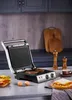 A kitchen counter with a grill, food, and kitchen accessories. Anteprima dell’immagine prodotto