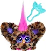 A close-up studio shot of a Furby Furblet toy with a leopard print pattern, bright pink hair, and large blue eyes. A teal accessory with ear-like shapes is positioned above and to the right of the toy. Produktbild-Vorschau