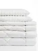A stack of white bedding items, including pillows and a duvet, against a white background. Produktbild-Vorschau