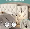 A close-up view of a tufted beige upholstered bed frame with integrated reading lamps and USB ports. Produktbild-Vorschau
