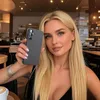 A woman is holding a black phone case in a cafe. Produktbild-Vorschau