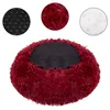 A round, plush dog bed with a black mesh center and a burgundy, long-haired exterior. Three circular insets show close-ups of the anti-slip bottom, the plush material, and the filling. Náhled obrázku produktu