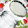 A set of black and white polka dot jar lids and a glass jar are shown with various salad ingredients floating around them. Podgląd zdjęcia produktu