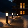 A pathway lined with bollard lights leads to a wooden cabin in a snowy environment at dusk. Produktbild-Vorschau