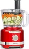 A red food processor filled with sliced cucumbers and shredded carrots, shown against a white background. Produktbild-Vorschau