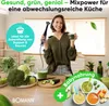 A woman is holding a blender and a glass of green juice in a kitchen setting, surrounded by fresh ingredients. Produktbild-Vorschau