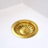 A close-up view of a gold sink drain in a white sink. Náhled obrázku produktu