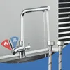 A chrome kitchen faucet with water running from it, set against a gray and black striped background. Two flexible hoses are visible in the foreground. Produktbild-Vorschau