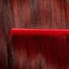 A close-up of red hair with a red comb. Anteprima dell’immagine prodotto