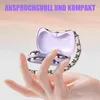 A hand holding a small, open purple case with two silver earbuds inside, with a chain strap attached to the case. Produktbild-Vorschau