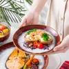 A person is holding a plate of food, with other plates and a bowl of soup visible. Náhled obrázku produktu