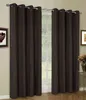 A window with brown curtains drawn to the sides, revealing a view of greenery outside. A framed picture hangs on the wall to the left, and a small table with flowers is visible on the right. Produktbild-Vorschau
