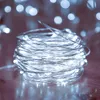 A close-up shot of a coil of white LED string lights on a wooden surface. Produktbild-Vorschau