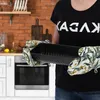 A person wearing oven mitts holds a black baking pan in a kitchen setting. Podgląd zdjęcia produktu
