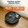 A black robot vacuum cleaner is shown in a corner of a room, near a wall and baseboard. Text overlays provide information about its features, such as corner cleaning coverage and distance from walls. Náhľad obrázku produktu