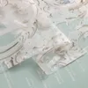 A close-up view of a sheer curtain with an ornate pattern, layered over a light blue background with text. Produktbild-Vorschau
