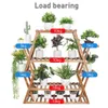 A wooden plant stand with multiple shelves displaying various potted plants. Anteprima dell’immagine prodotto