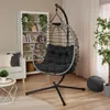 A hanging egg chair with a black cushion is placed in a living room next to a bookshelf and a sofa. Produktbild-Vorschau