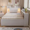 A bedroom scene featuring a white bed with a headboard shelf, bedside table, and a window with a windowsill. Náhled obrázku produktu