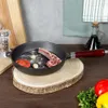 A cast iron pan with food items on a wooden board, with vegetables and oil bottle in the background. Produktbild-Vorschau