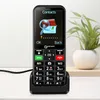 A black Geemarc senior phone is shown in its charging dock on a white surface, with a potted plant in the background. Produktbild-Vorschau