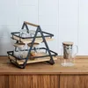 A two-tiered serving stand with glasses and jars on a wooden countertop, with white tiled backsplash. Podgląd zdjęcia produktu