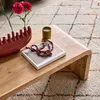 A close-up of a wooden coffee table with decorative items on it, placed on a rug. Produktbild-Vorschau