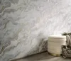 A wall with marble-patterned wallpaper and a decorative ottoman in the corner. Produktbild-Vorschau