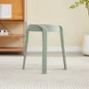 A single green stool is shown in a room with a shelf unit in the background and a plant in a pot on the right. Voir les images du produit