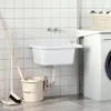 A white resin sink mounted on a tiled wall in a laundry room, with a washing machine and cleaning supplies nearby. Produktbild-Vorschau