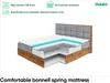 A cutaway view of a mattress showing its internal layers, placed on a bed frame. Produktbild-Vorschau