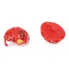 Two red Bakugan toys are shown against a white background. One is partially open, revealing a clear plastic interior and a yellow emblem. The other is closed and viewed from the bottom. Náhľad obrázku produktu