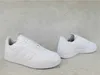 A pair of white Adidas sneakers are displayed on a light gray, textured surface. Voir les images du produit