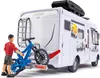 A toy camper van with a person and a bicycle attached to the back. Voir les images du produit