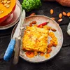 A close-up of a prepared dish with accompanying ingredients on a dark wooden surface. Produktbild-Vorschau