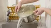 A person is pouring water from a pot into a sink. Anteprima dell’immagine prodotto
