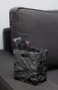Schwarze Knitterbox mit Fernbedienungen und anderen Eingabegeräten auf der Wohnzimmercouch Produktbild-Vorschau