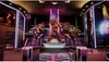 A large golden animatronic statue stands on a platform in a brightly lit, futuristic arcade or entertainment venue. Podgląd zdjęcia produktu