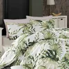 A close-up view of a bed with bedding featuring a green leaf pattern. Produktbild-Vorschau